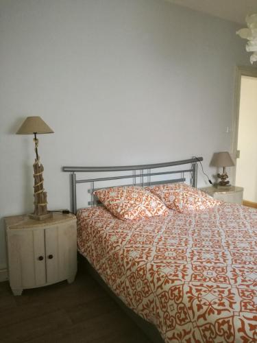 1 Schlafzimmer mit einem Bett mit orangefarbener und weißer Tagesdecke in der Unterkunft "Côté nature", appartement cosy au cœur de Munster in Munster