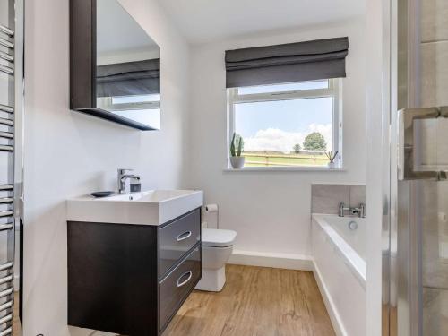 a bathroom with a sink and a toilet and a window at 3 Bed in Ashford In The Water 88675 in Great Longstone