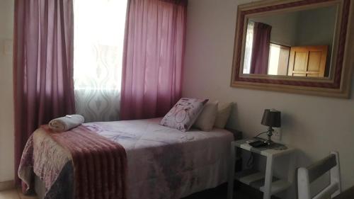 a small bedroom with a bed and a mirror at Apollo Guest House in Mahikeng