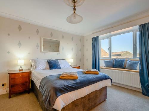 a bedroom with a bed and a window with blue curtains at 3 Bed in Cockermouth 89139 in Aspatria