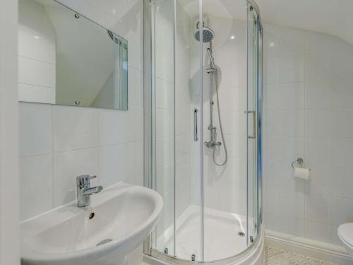 La salle de bains blanche est pourvue d'un lavabo et d'une douche. dans l'établissement 4 Bed in Braunton 89603, à Braunton