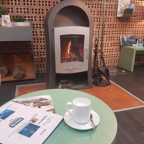 - une tasse de café sur une table devant une cheminée dans l'établissement Kyriad Angoulême Nord Champniers- Hôtel & Résidence, à Champniers