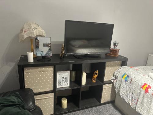 a tv on a shelf next to a bed at Feel at home in Abbey Wood