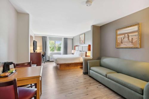 um quarto de hotel com um sofá e uma cama em Ramada by Wyndham Saco/Old Orchard Beach Area em Saco