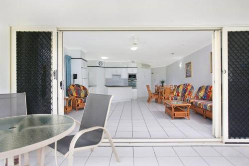 a living room with a glass table and chairs at Absolute beachfront apartment in Trinity Beach