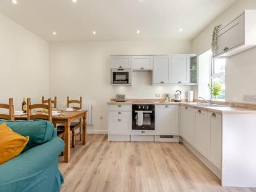 uma cozinha e sala de jantar com armários brancos e uma mesa em The Barrels at Leintwardine em Leintwardine