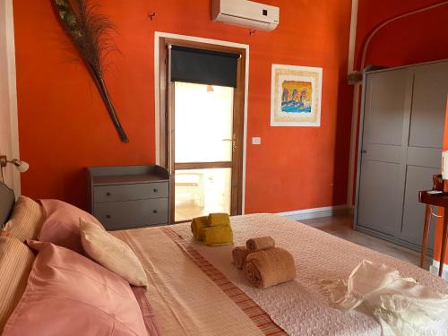 a bedroom with orange walls and a bed with two towels at Hotel Villa Belfiori in Torre Dei Corsari