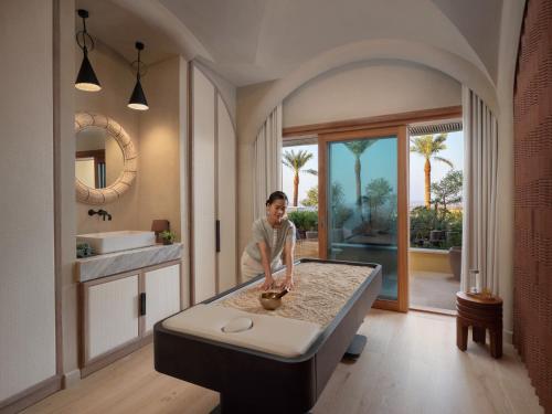 a young boy sitting on a bed in a bathroom at Six Senses Southern Dunes, The Red Sea in Khuff