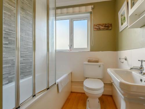 a bathroom with a toilet and a sink and a window at 3 Bed in Syderstone 89756 in Syderstone
