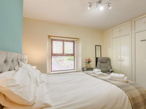 um quarto com uma grande cama branca e uma cadeira em 3 Bed in Llanfairfechan 89646 em Llanfairfechan
