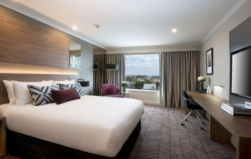 a hotel room with a bed and a desk and a window at Rydges South Bank Brisbane in Brisbane
