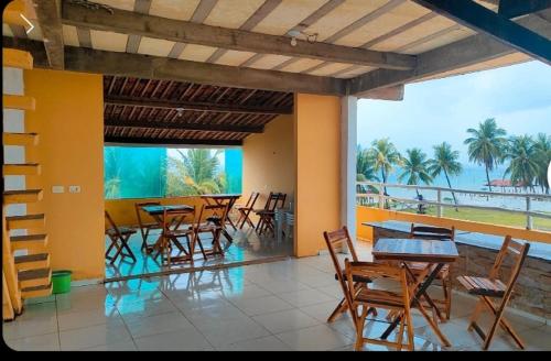 a room with tables and chairs and a view of the ocean at Pousada Pé na Areia in São José da Coroa Grande