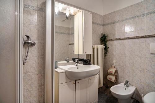 uma casa de banho branca com um lavatório e um espelho em Beb chalet bella vita Trento em Vignola