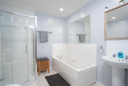 een witte badkamer met een douche, een bad en een wastafel bij Belfast 2 Bed Apartment in Belfast