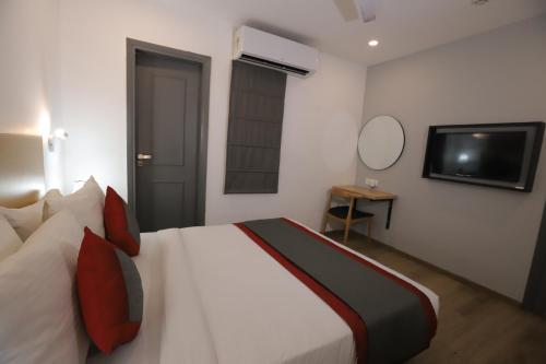 a bedroom with a bed and a tv on the wall at Qotel Comfort IP Residency East Delhi Preet Vihar in New Delhi