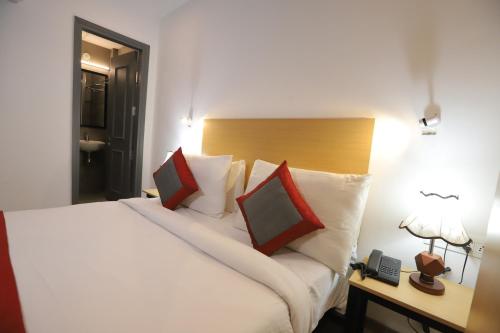 a bedroom with a large white bed with red pillows at Qotel Comfort IP Residency East Delhi Preet Vihar in New Delhi