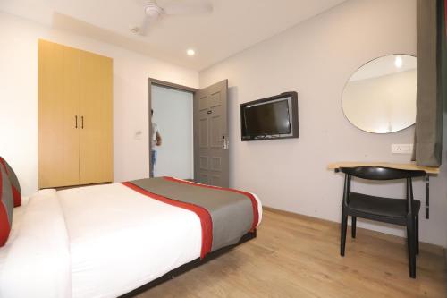 a bedroom with a bed and a desk and a mirror at Qotel Comfort IP Residency East Delhi Preet Vihar in New Delhi