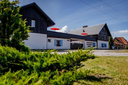 a black and white barn with red umbrellas at Dom Wczasowy Lazur in Wicie