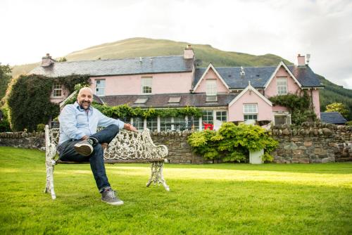 a man sitting on a bench in the grass at Monachyle Mhor Hotel in Lochearnhead
