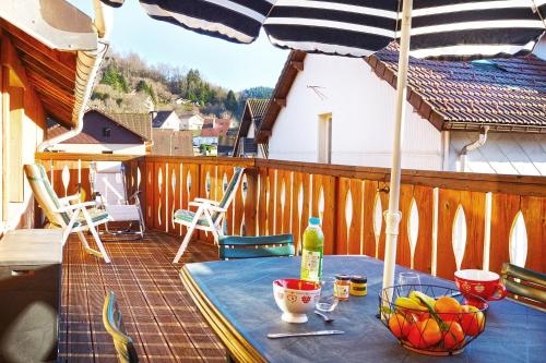 - une table avec un bol de fruits et un parasol sur le balcon dans l'établissement Comme Chez Soi - Vue montagne et garage privé, à La Bresse