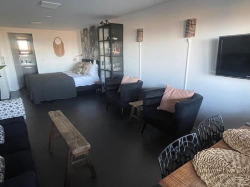 a living room with a bed and a couch and chairs at B&B Zeespiegel in Zandvoort