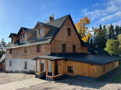 a large wooden house with a gambrel roof at Apartmány Horský Dvůr in Bedřichov
