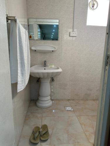 a bathroom with a sink and a mirror and two shoes at Al Ramla, Na’eem Bin Masoud St#8, Villa#10 in Sharjah