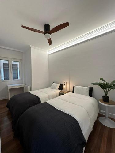 two beds in a bedroom with a ceiling fan at Central Moyua By Sleep In Bilbao in Bilbao