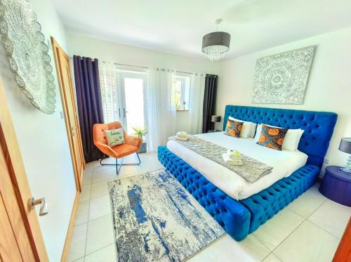 a bedroom with a blue bed and an orange chair at CORNWALL LUXURIOUS UNIQUE New Build PALMA VILLA# 4miles EDEN PROJECT, BEACH & HARBOUR # Private Location, Encllosed Garden with View, Underfloor Heating, Coffee Machine# Walking-Cycling Path, Pet Friendly in St Austell