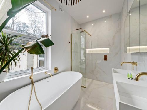 Baño blanco con bañera y lavamanos en Pass the Keys Modern and luxury London house en Londres