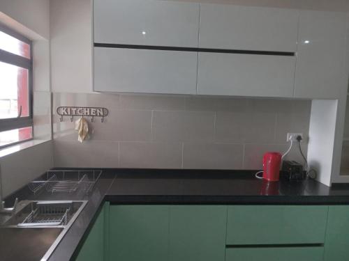 a kitchen with white cabinets and a black counter top at Chaya accommodation B&B and self catering in Mzuzu