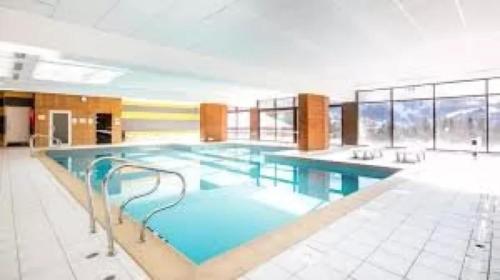 a large swimming pool with blue water in a building at Appartement Valloire 6-8 pers in Valloire
