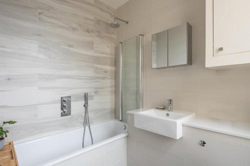 La salle de bains blanche est pourvue d'un lavabo, d'une baignoire et de toilettes. dans l'établissement Veeve - Good Vibrations, à Londres