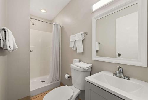 a white bathroom with a toilet and a sink at Rodeway Inn in Charlotte
