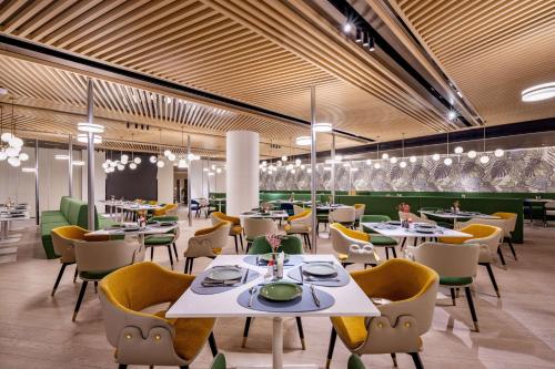 um restaurante com mesas brancas e cadeiras amarelas em Hilton Garden Inn Nanjing Hexi Olympic Sports Center em Nanquim
