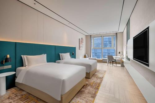 um quarto de hotel com duas camas e uma televisão de ecrã plano em Hilton Garden Inn Nanjing Hexi Olympic Sports Center em Nanquim