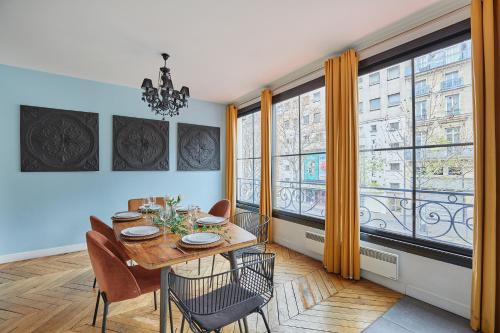 - une salle à manger avec une table, des chaises et de grandes fenêtres dans l'établissement Residence Centre de Paris by Studio prestige, à Paris