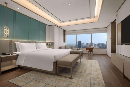 een slaapkamer met een groot wit bed en een bureau bij Wyndham Hangzhou Linping in Hangzhou