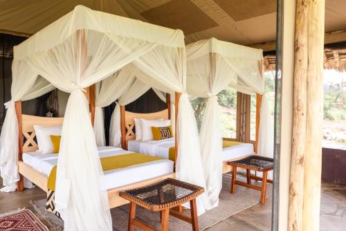two beds in a room with mosquito nets at Soroi Cheetah Tented Camp in Mwatate