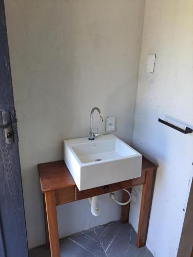 łazienka z białą umywalką na drewnianym stole w obiekcie Loft na Rondinha w mieście Arroio do Sal