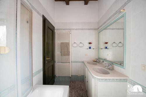 Baño blanco con lavabo y espejo en Villa Cycas, en Polpenazze del Garda