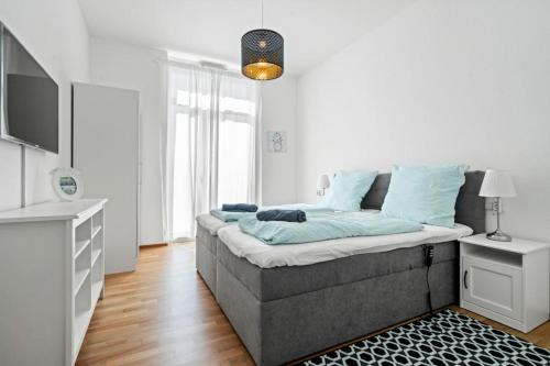 een witte kamer met een bed met blauwe kussens bij Bodensee-Oase IStayUnixI Seenähe-Suite-Terrasse-Netflix-Parkplatz in Friedrichshafen