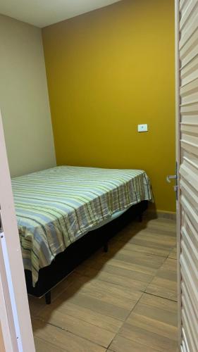 a small bed in a room with a yellow wall at Casa flet em serrambi praia in Porto De Galinhas
