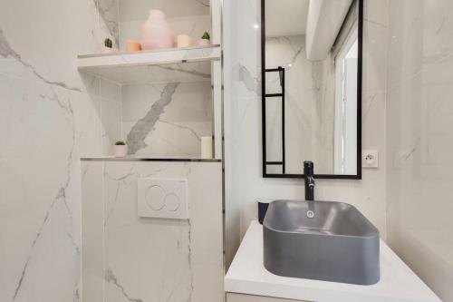 une salle de bain avec un lavabo et un miroir dans l'établissement Appartement Moderne au coeur du 7ème, à Paris