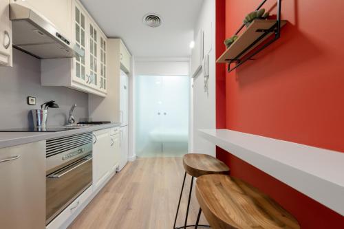 uma cozinha com uma parede vermelha e uma cadeira de madeira em Centric and bright- 1Bd 1Bth- San Bernardo em Madri