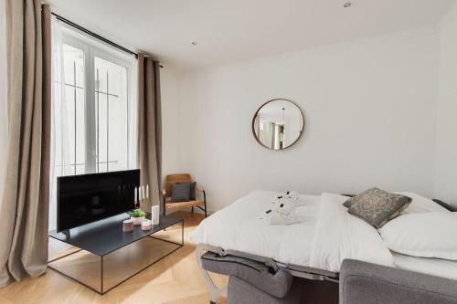 une chambre blanche avec un lit et un miroir dans l'établissement Appartement Moderne au coeur du 7ème, à Paris