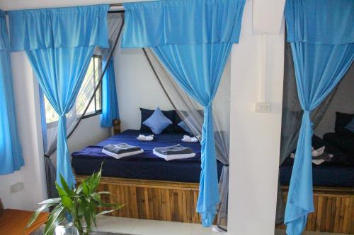 a bed in a room with blue curtains at Rainbow Lodge in Koh Kong