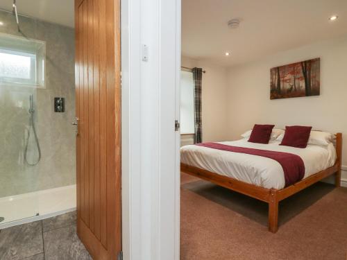 um quarto com uma cama e uma cabina de duche ao nível do chão em 8 Little Mell Fell em Penrith