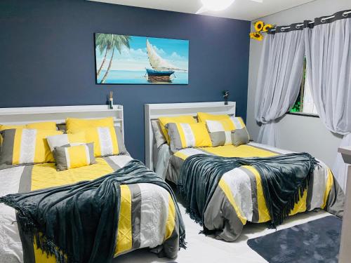 a bedroom with two beds with yellow and black sheets at Villa Paradise in Brazil - Praia de Guaratiba Prado-BA in Prado