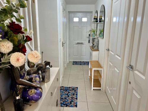 a hallway with a white door and a vase of flowers at Driver Way in Wellingborough